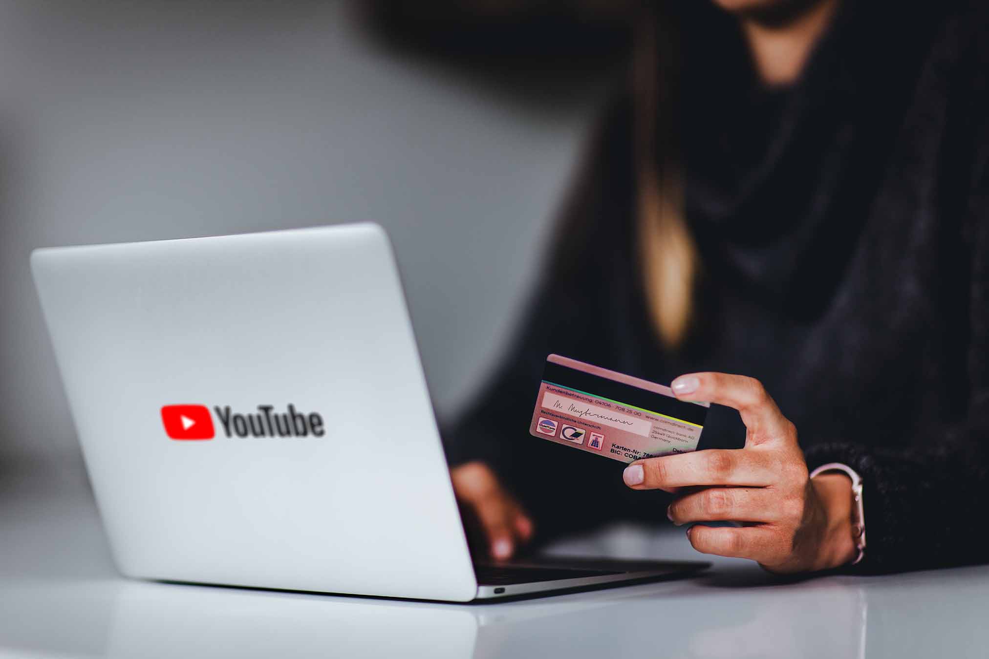 a-woman-infront-a-laptop-with-youtubes-logo-holding-a-credit-card